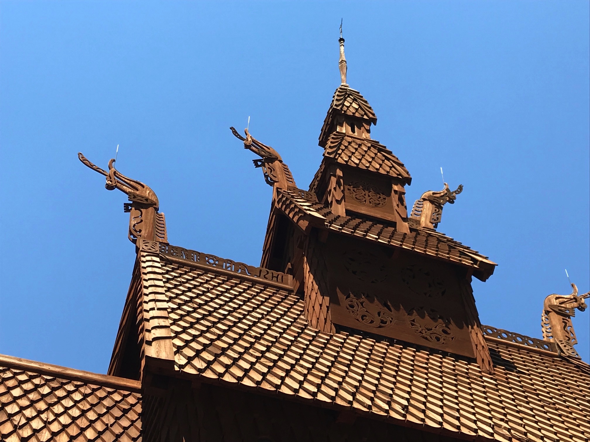 The roof of a wooden church with unique wooden sculptures and steeple on the top
