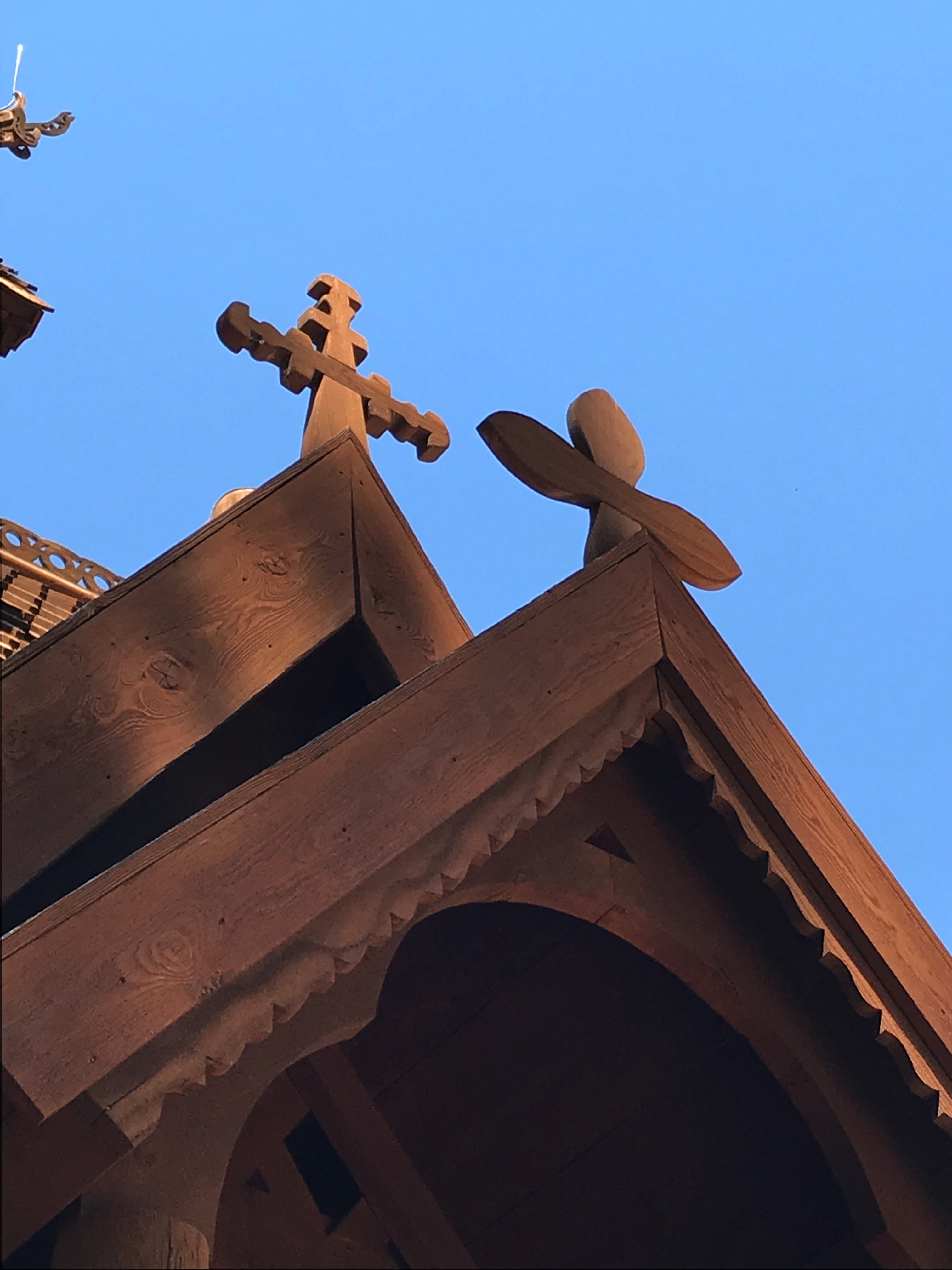 The roof of a wooden church with multiple wooden crosses coming off the top 