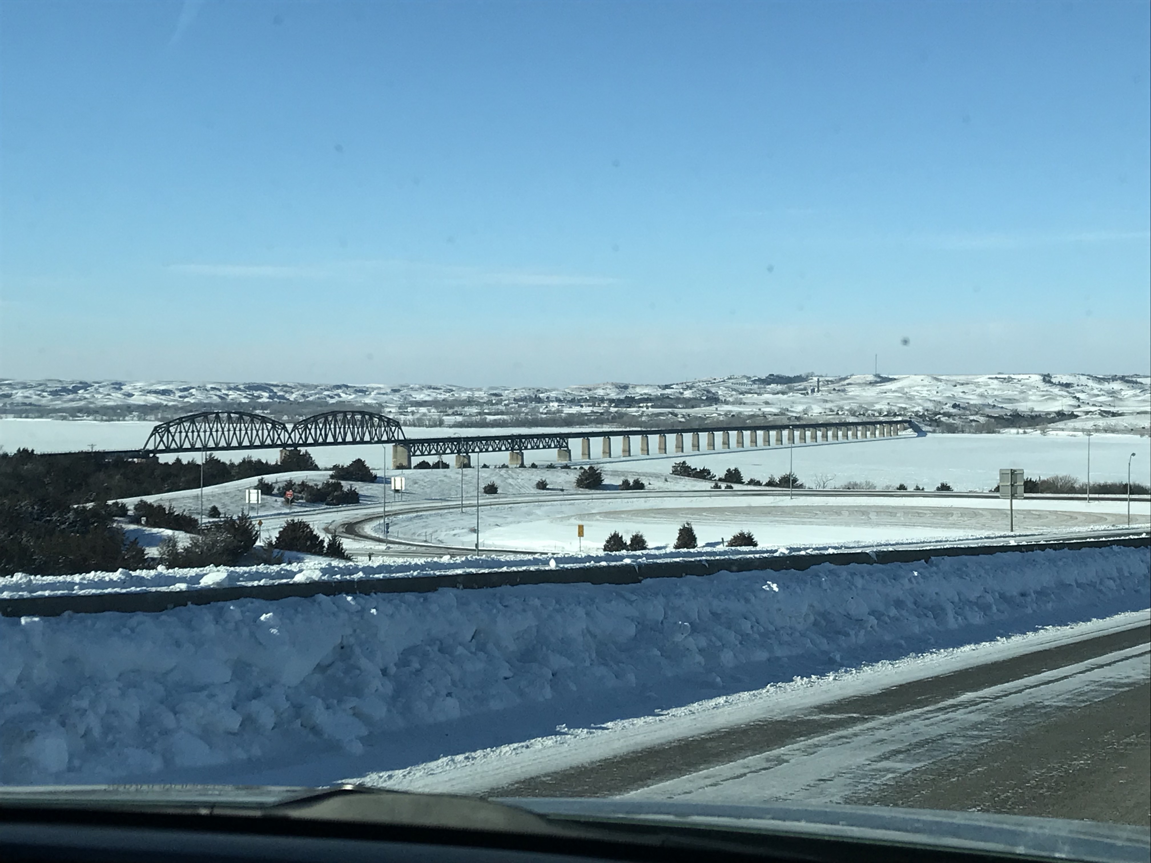 A snowy landscape and a long, railroad bridge over the ice-covered Missouri River